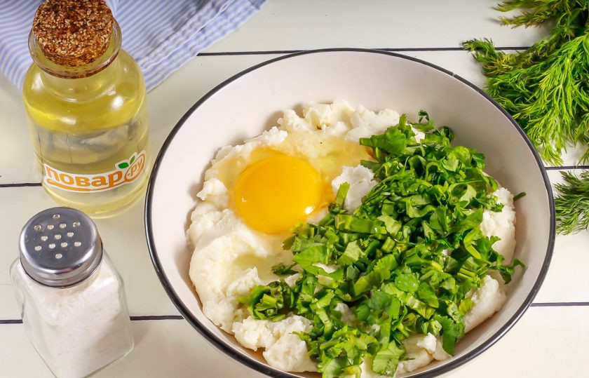 1. Этап. Сырники с кинзой: Творог выложите в глубокую емкость и разомните вилкой. Промойте кинзу и срежьте стебли. Зелень нарежьте лентами и добавьте в емкость к творогу. Вбейте куриное яйцо, всыпьте соль и все тщательно перемешайте.