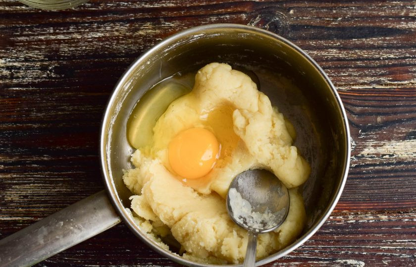 1. Этап. Профитроли с ванильным кремом: Вбейте по одному яйца. Хорошо перемешайте тесто.