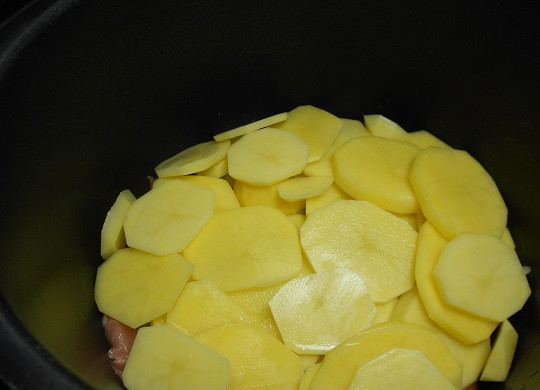 1. Этап. Свинина с помидорами и картофелем в мультиварке: 4. Мясо с луком посолить и поперчить по вкусу. При желании можно добавить немного специй для мяса или сушеных трав. Чтобы дополнить блюдо гарниром очистить и нарезать тонкими ломтиками картофель. Подсолить немного и выложить в чашу мультиварки.