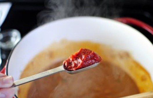 1. Этап. Курица с чили и фасолью: Через минуту влейте бульон и молоко, доведите до кипения и добавьте томатную пасту.