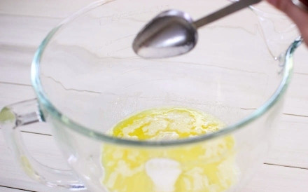 1. Этап. Булочки с начинкой: 3. Растопите сливочное масло, немного остудите его. Отдельно взбейте вилкой яйца. Соедините масло с яйцами, всыпьте щепотку соли.