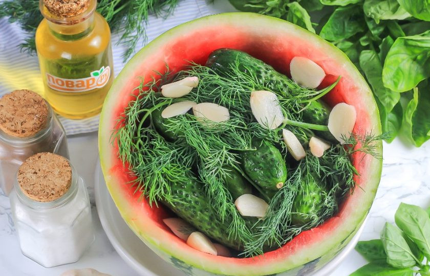 1. Этап. Малосольные огурцы в арбузе: Промойте укроп, очистите зубчики чеснока и нарежьте слайсами. Добавьте к огурцам вместе с горошинами черного перца.