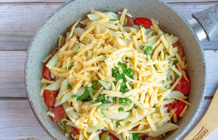 1. Этап. Паста с помидорами и маслинами: Выложите на сковороду пасту, петрушку и сыр.