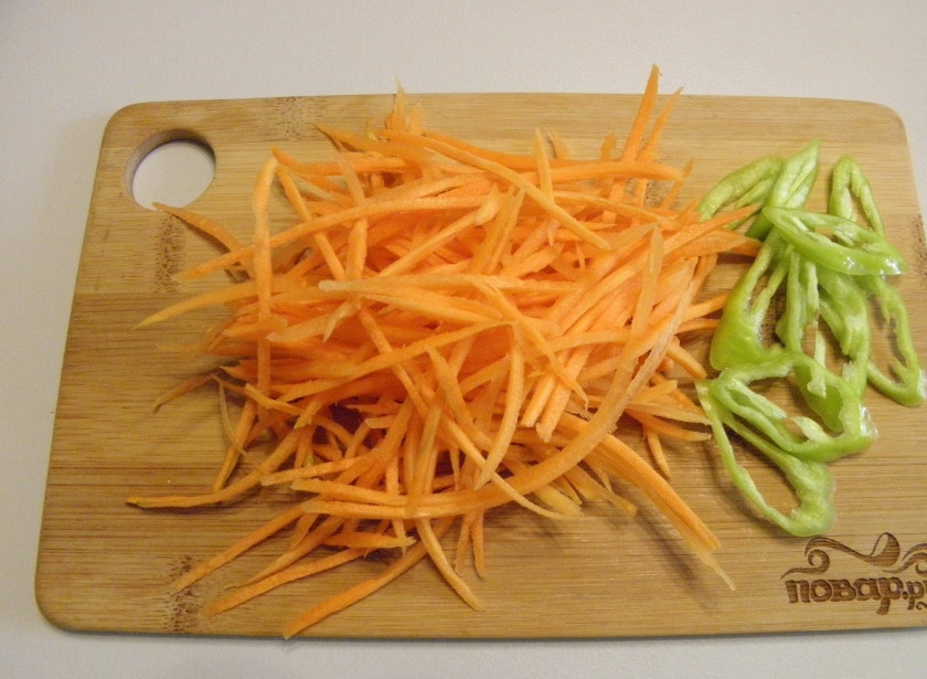 1. Этап. Пикантные огурчики на зиму: Морковь натрите на крупной терке или терке для приготовления моркови по-корейски. Острый перец порежьте тонкими колечками.