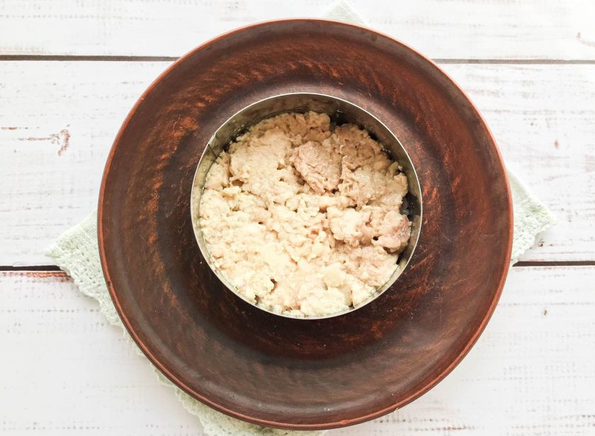 1. Этап. Салат Диана с печенью трески: Поверх риса выложите печень трески, предварительно размяв ее вилкой.