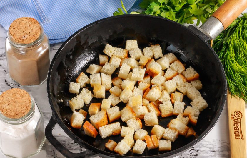 1. Этап. Салат с фасолью, сосисками, сыром и сухариками: Ломтики хлеба нарежьте кубиками и поджарьте в сковороде примерно 3-5 минут до румяности. Можно слегка полить их растительным маслом.