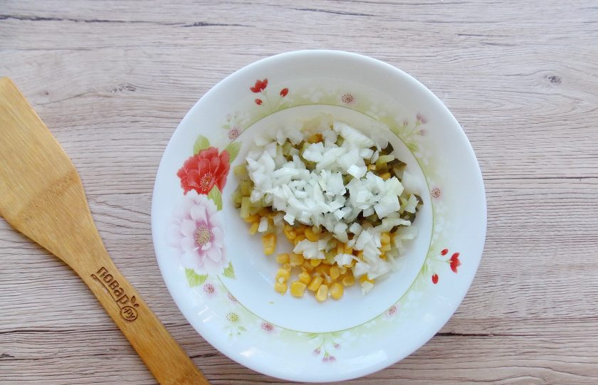 1. Этап. Салат Желтый одуванчик с кукурузой: Репчатый лук очистите, помойте, мелко нарежьте и добавьте к остальным ингредиентам в миску.