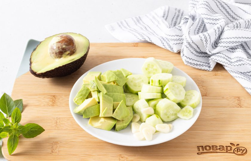 1. Этап. Холодный суп из авокадо: Огурцы очистите от кожуры и нарежьте ломтиками, чеснок очистите и порежьте пластинами. Авокадо разрежьте пополам, очистите от кожуры и удалите косточку, порежьте крупными кубиками.