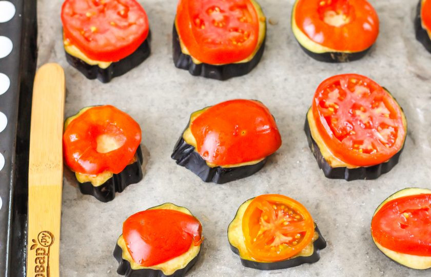 1. Этап. Медальоны из баклажанов: Выложите на баклажаны ломтики помидоров. Разогрейте духовку до 200 градусов и запеките в ней овощи примерно 15 минут до мягкости баклажанной нарезки.