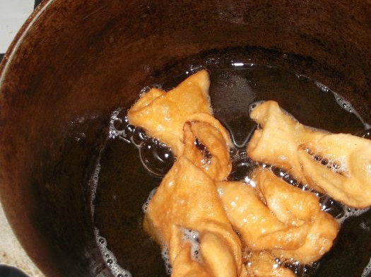 1. Этап. Хворост тонкий хрустящий без водки: Теперь берем квадратик и просовываем один краешек в прорезь. Так проделываем с каждым. После чего наливаем в глубокую сковороду растительное масло и нагреваем на плите. Если у вас есть фритюрница, используйте ее. В раскаленное масло закладываем завернутые квадратики и обжариваем с двух сторон.