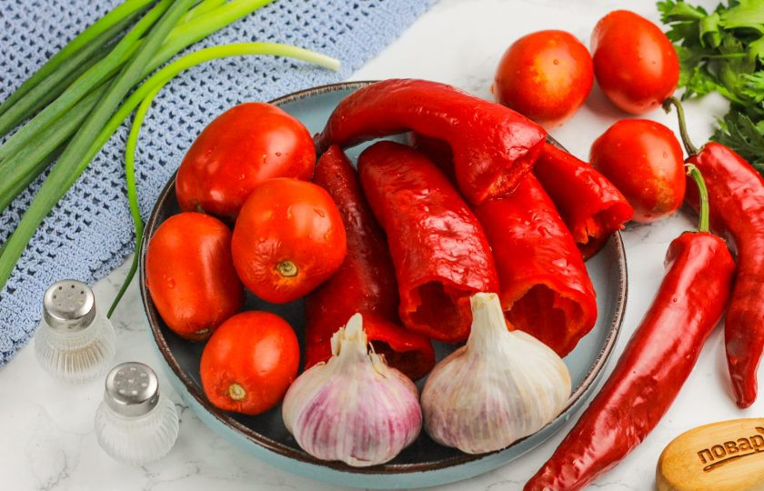 1. Этап. Бродячая аджика: Подготовьте указанные продукты. Промойте и очистите болгарский перец от семян, из помидоров вырежьте зеленые сердцевинки. Чесночные зубчики очистите от шелухи и промойте вместе с горьким перцем (с него срежьте хвостики). Если хотите уменьшить горечь, то удалите и семена.