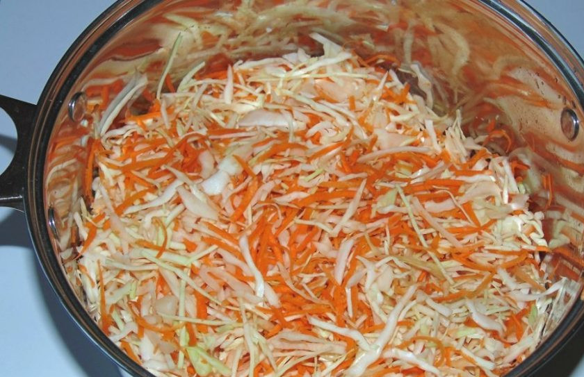 1. Этап. Засолка капусты горячим рассолом: Перемешайте в большой ёмкости капусту с морковью. Обомните овощи руками.