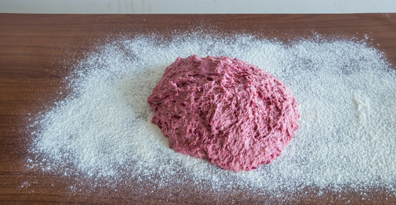 1. Этап. Штоллен с пьяной вишней: Разогрейте духовку до 220 ˚С. Разделите тесто пополам. Выложите тесто на посыпанную мукой рабочую поверхность, сформируйте овальную буханку. Скалкой или ребром ладони слегка придавите тесто, разделяя буханку на две неравные части: 2/3 и 1/3. Заверните меньшую часть на большую, придавая штоллену форму спеленутого младенца.