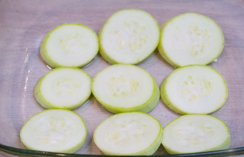 1. Этап. Кабачки с помидорами и сыром в духовке: Каждый кусочек кабачка посолим и поперчим. Форму для запекания нужно смазать маслом. Уложите кабачки в один слой в форму. Можно немножко посолить.