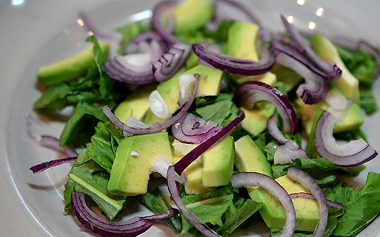 1. Этап. Салат с пряной тыквой Осенний блюз: Выложите рукколу, ломтики авокадо, тонкие полукольца лука.