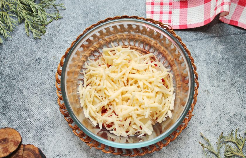 1. Этап. Салат с помидорами, ананасом и сыром: Твердый сыр натрите на крупной терке и добавьте в салатник.
