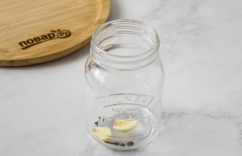 1. Этап. Маринованный топинамбур: На дно чистой стерилизованной баночки выложите душистый и черный перец, гвоздику и чеснок.