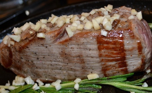 1. Этап. Говядина с розмарином в духовке: Почистите и мелко нарежьте два зубчика чеснока. Добавьте его вместе с розмарином на сковороду к говядине минут на 10. В это время поставьте разогреваться духовку до 180 градусов.