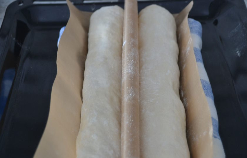 1. Этап. Пшеничный багет: Приподнимите бумагу для выпечки между багетами, как бы образуя бортик, с боков подложите свернутую рулоном салфетку.