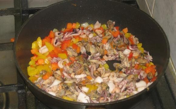 1. Этап. Сифудо тяхан: Разогрейте масло на сковороде. Добавьте в неё нарезанный лук и морковь. Жарьте их до мягкости. Затем внесите перец кубиками. Перемешайте ингредиенты и готовьте их пару минут. Потом добавьте морепродукты. Жарьте продукты вместе 7 минут.