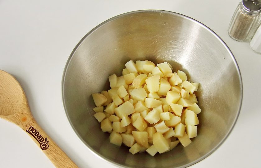 1. Этап. Салат Оливье на год Крысы: Картофель очистите от кожуры, нарежьте небольшими кубиками и переложите в глубокую миску.