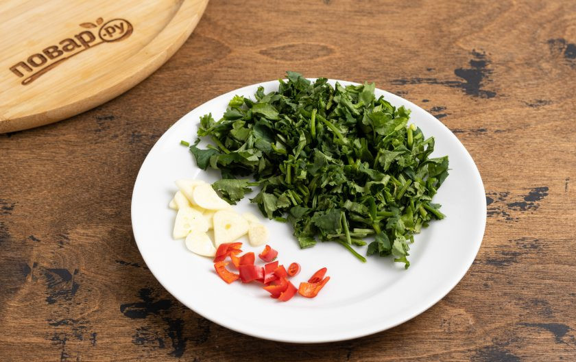 1. Этап. Соус из чернослива на зиму: Острый перец очистите от семян и порежьте кружочками. Чеснок очистите от шелухи и порежьте пластинами. Петрушку и базилик помойте, обсушите и мелко порежьте.