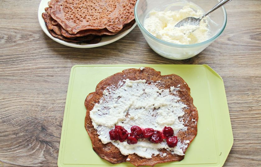 1. Этап. Шоколадные блины с вишней: Нанесите творожную массу на одну поверхность блинов, разложите вишню в один ряд по краю и сверните в закрытые рулетики и подавайте к столу.