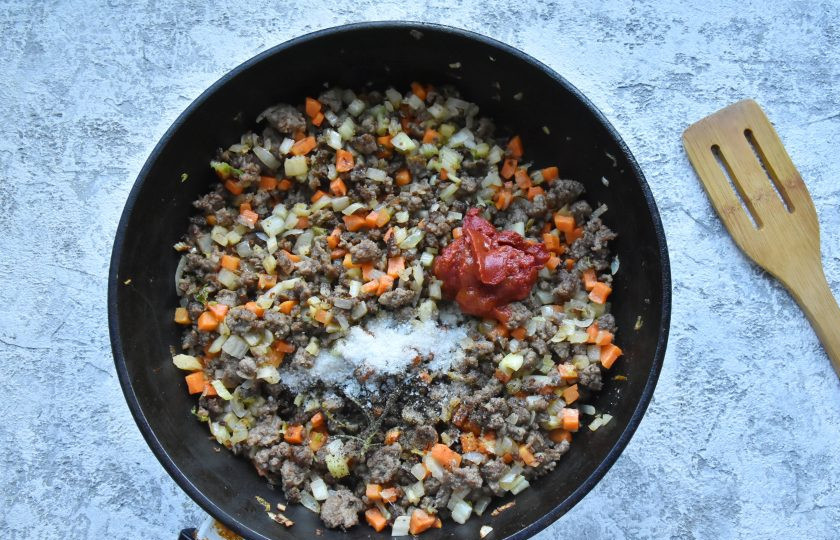 1. Этап. Лазанья с фаршем от Джейми Оливера: Посолите рагу и добавьте молотый черный перец по вкусу. Добавьте томатную пасту и перемешайте.