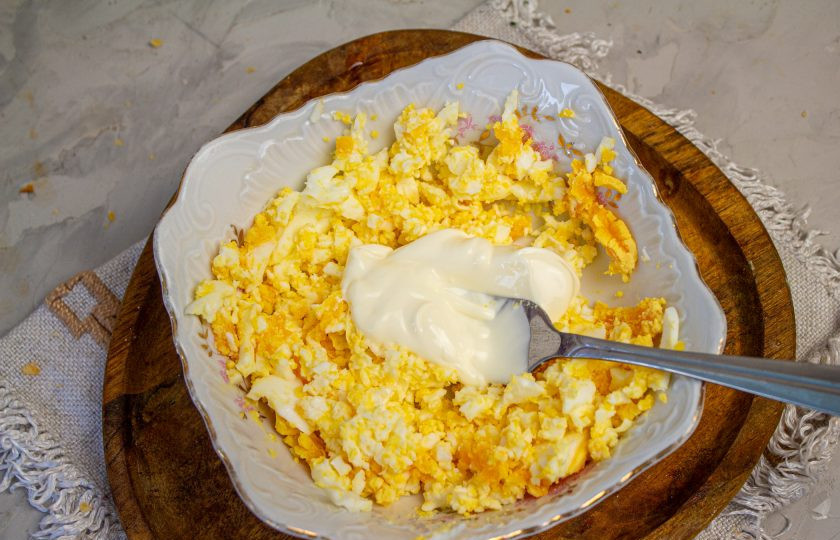 1. Этап. Салат Ананасовое кольцо: Куриные яйца отварите вкрутую, остудите и натрите мелко. Смешайте яйца с ложкой майонеза.