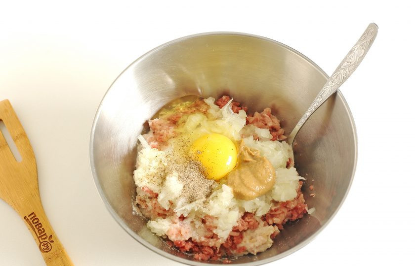 1. Этап. Курино-говяжьи котлеты в духовке: Добавьте тертый на крупной терке лук, яйцо, соль и специи по вкусу.