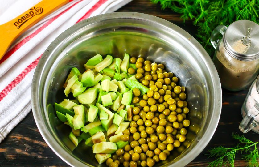 1. Этап. Кето-оливье: Очистите от кожуры авокадо, удалите косточку и нарежьте мякоть средними кубиками. Высыпьте в глубокий салатник и сбрызните лимонным соком, перемешайте. Это делается, чтобы мякоть не потемнела. Слейте маринад с консервированного зеленого горошка. Высыпьте его в емкость.