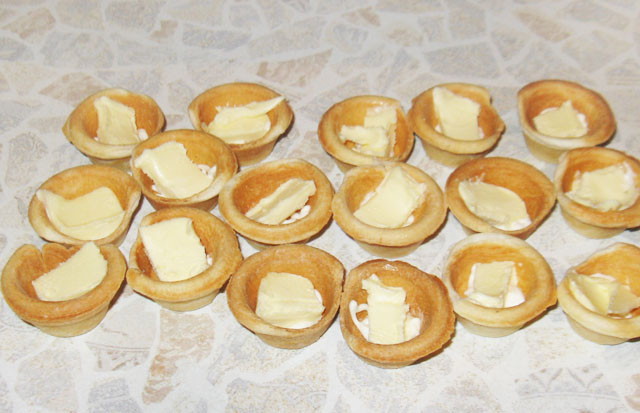 1. Этап. Тарталетки с икрой и маслом: 2. Сливочное масло заранее лучше достать из холодильника, чтобы оно было мягкое. На дно тарталетки выложить небольшой кусочек масла, а при желании аккуратно размазать его по всей поверхности. Количество масла зависит от ваших вкусовых предпочтений.