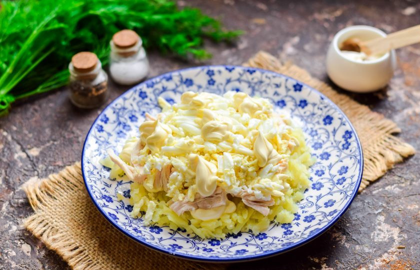 1. Этап. Салат Лебединый пух с пекинской капустой: Куриные яйца отварите вкрутую, очистите и натрите на средней терке. Выложите яйца поверх курицы, смажьте майонезом.