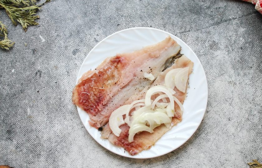 1. Этап. Лещ запеченный в тесте: Репчатый лук порежьте полукольцами и половину выложите на одну половину рыбы, немного посолите. Закройте лук второй половинкой.