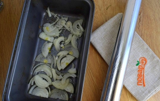 1. Этап. Мойва, запеченная в фольге в духовке: Форму для запекания смажьте растительным маслом. Выложите слой лука, нарезанного полукольцами. Немного посолите.