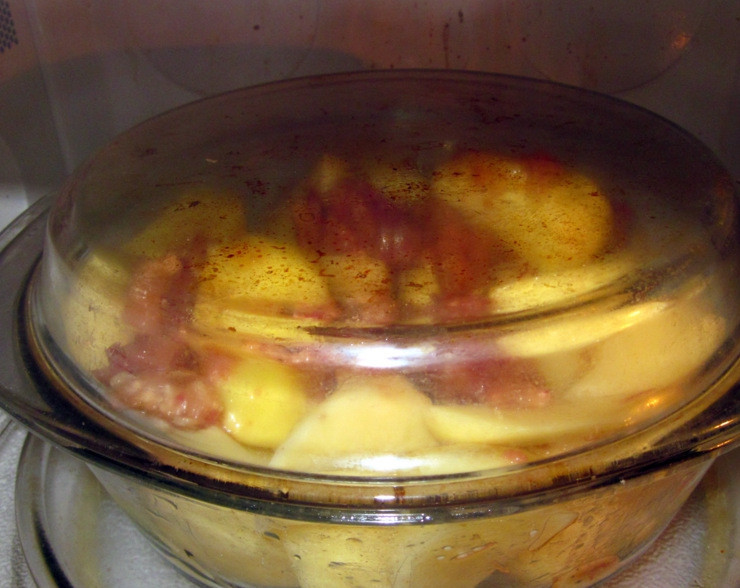 1. Этап. Жаркое с тушенкой: 3. Накрываем сверху крышкой или подходящей по размеру стеклянной миской. На полной мощности тушим 30-40 минут, через каждые 15 минут достаем, перемешиваем, и проверяем картошку на готовность.