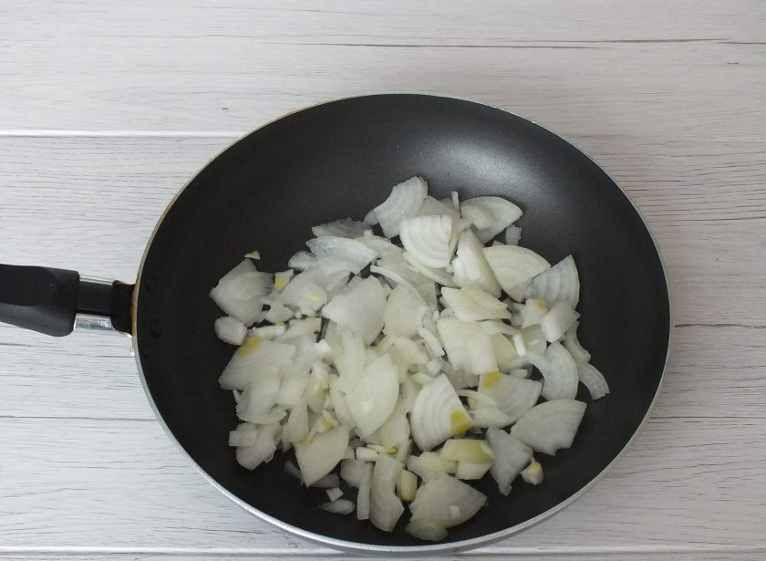 1. Этап. Фаршированная голень индейки в духовке: Почистите лук, нарежьте четверть колечками, переложите в сковороду. Добавьте 3 ст.л. растительного масла.
