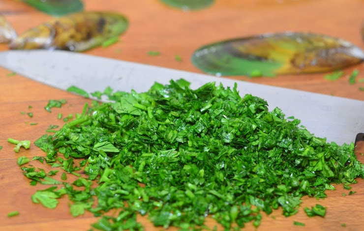 1. Этап. Мидии с сыром: Зелень вымойте и обсушите. Затем обрежьте стебельки, а листики нарубите острым ножом как можно мельче.