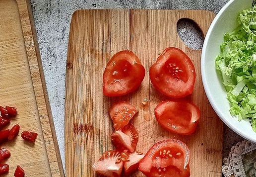 1. Этап. Овощной салат с колбасными снеками: Помидор нужно разрезать и удалить мякоть из него. Оставить только твёрдую часть. Мякоть используйте в другом блюде. Я в салате буду использовать пекинскую капусту - ярко зелёные листики у неё. Берём салатник, выкладываем пекинскую капусту.