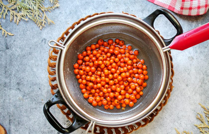 1. Этап. Компот из красной рябины на зиму: Слейте отвар в кастрюлю, а ягоды верните в банку.