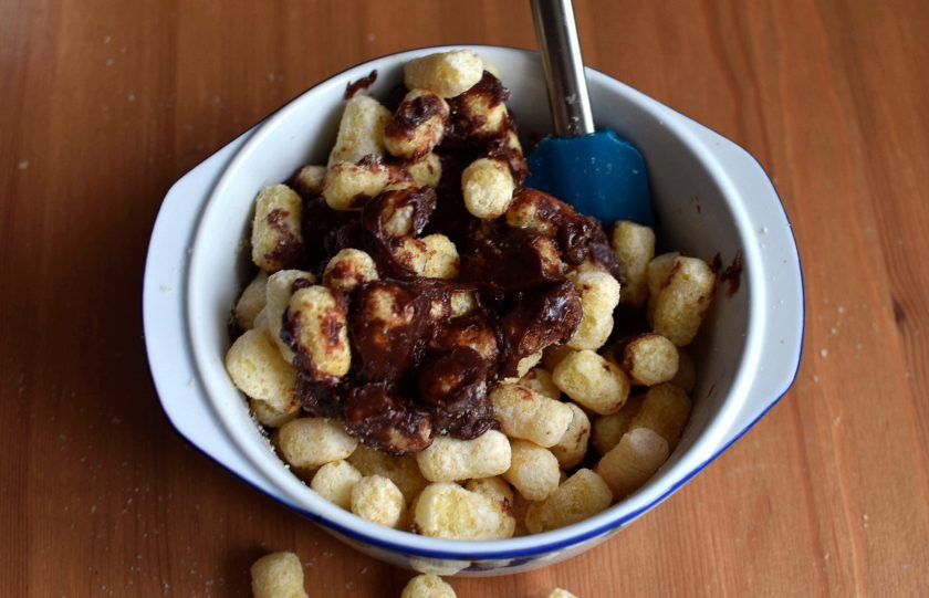 1. Этап. Торт из кукурузных палочек: В горячую массу выложите половину кукурузных палочек и быстро перемешайте. Затем выкладывайте оставшиеся палочки частями и хорошо перемешивайте каждую порцию.