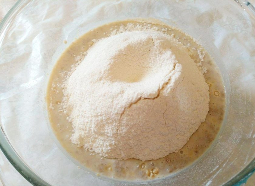 1. Этап. Булочки «Соломбальские»: Всыпьте в опару просеянную кукурузную муку, а затем 200 грамм просеянной пшеничной муки, перемешайте до однородности.