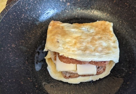 1. Этап. Омлетный сэндвич с индейкой: Поддеваем лопаткой или вилкой свободную сторону омлета и кладем её на начинку. Обжариваем сэндвич с двух сторон. Накрываем крышкой, доводим до готовности до расплавления сыра.