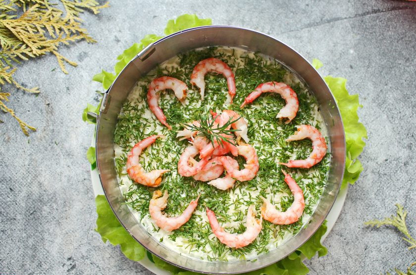 1. Этап. Салат с красной рыбой и креветками слоями: Креветки очистите от панциря и головы. Зелень порежьте и посыпьте верх салата, украсьте отварными креветками. Уберите салат в холодильник на 15 минут, затем подавайте к столу.