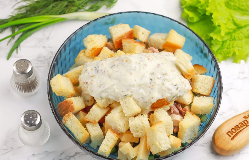 1. Этап. Салат Тёщин: Измельчите зеленый лук и добавьте вместе с поджаренными сухариками в емкость. Выложите заправку и аккуратно все перемешайте.