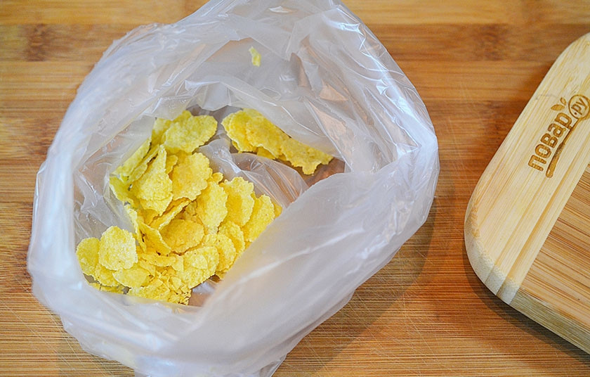 1. Этап. Деревенский картофель под сырным соусом: Кукурузные хлопья положите в пакет, затем измельчите или прокатайте скалкой до измельчения.