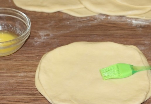 1. Этап. Пирожки из слоеного теста на кефире: 10. Формируем из кружков стопки по 4 круга, и смазываем кружочки растопленным сливочным маслом.