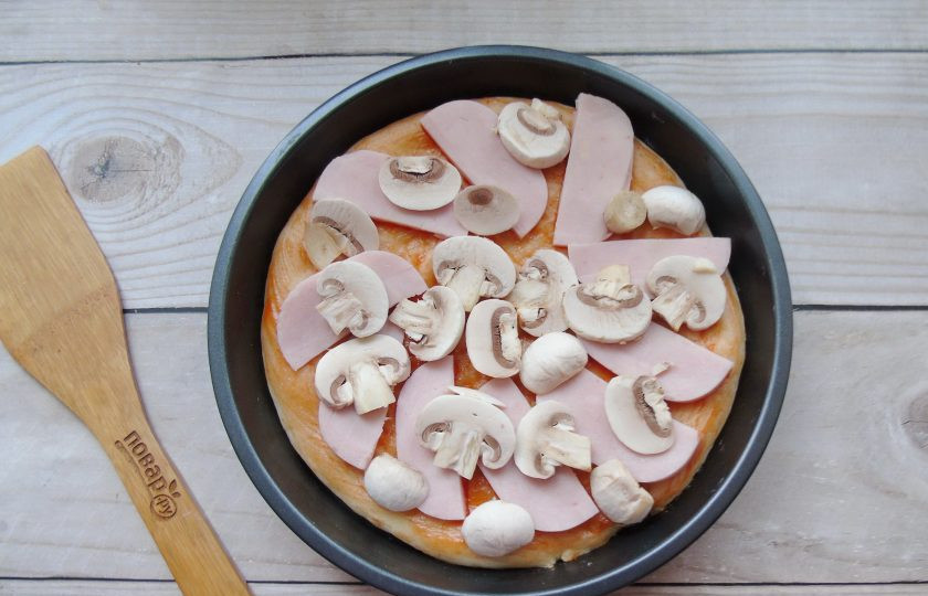 1. Этап. Пицца с ветчиной и грибами: Нарежьте пластинками ветчину и шампиньоны. Выложите на тесто.