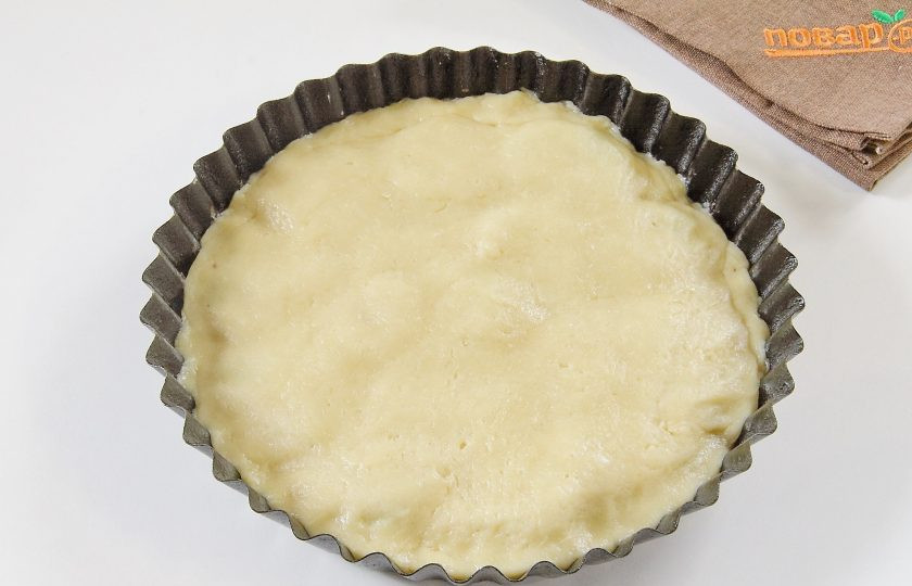 1. Этап. Пирог-перевертыш с киви и кедровыми орешками: Достаньте тесто и раскатайте его в форме круга по размеру чуть больше формы. Накройте тестом начинку и подверните внутрь края.