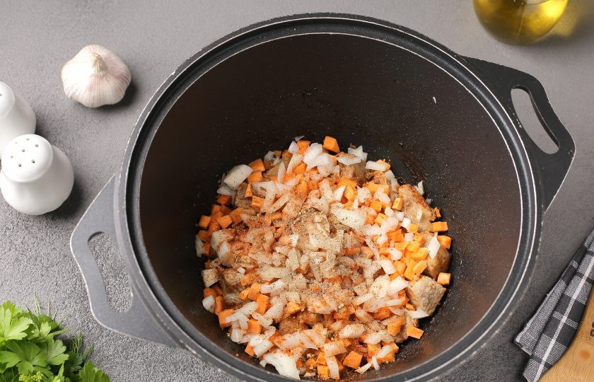 1. Этап. Картошка тушёная со свининой и фасолью: Добавьте нарезанные кубиками лук и морковь, соль и специи по вкусу. Перемешайте и обжарьте мясо с овощами в течение 5 минут.